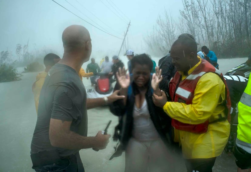 Voluntarios rescatan a una mujer incomunicada por el agua en la zona cerca del Puente de Causarina in Freeport, Grand Bahama. (AP)