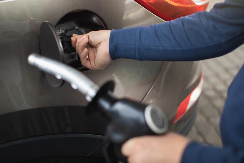 Una persona retira la tapa del tanque de su vehículo para reabestecerlo de gasolina.