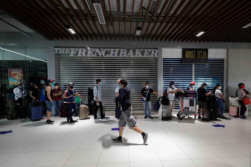 Personas realizan fila en espera por un viaje de autobús para regresar a sus provincias en Filipinas. (AP)