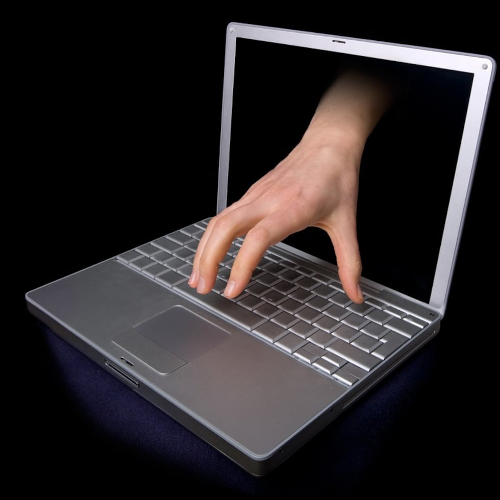 A hacker concept image of a hand coming through the computer. computer virus