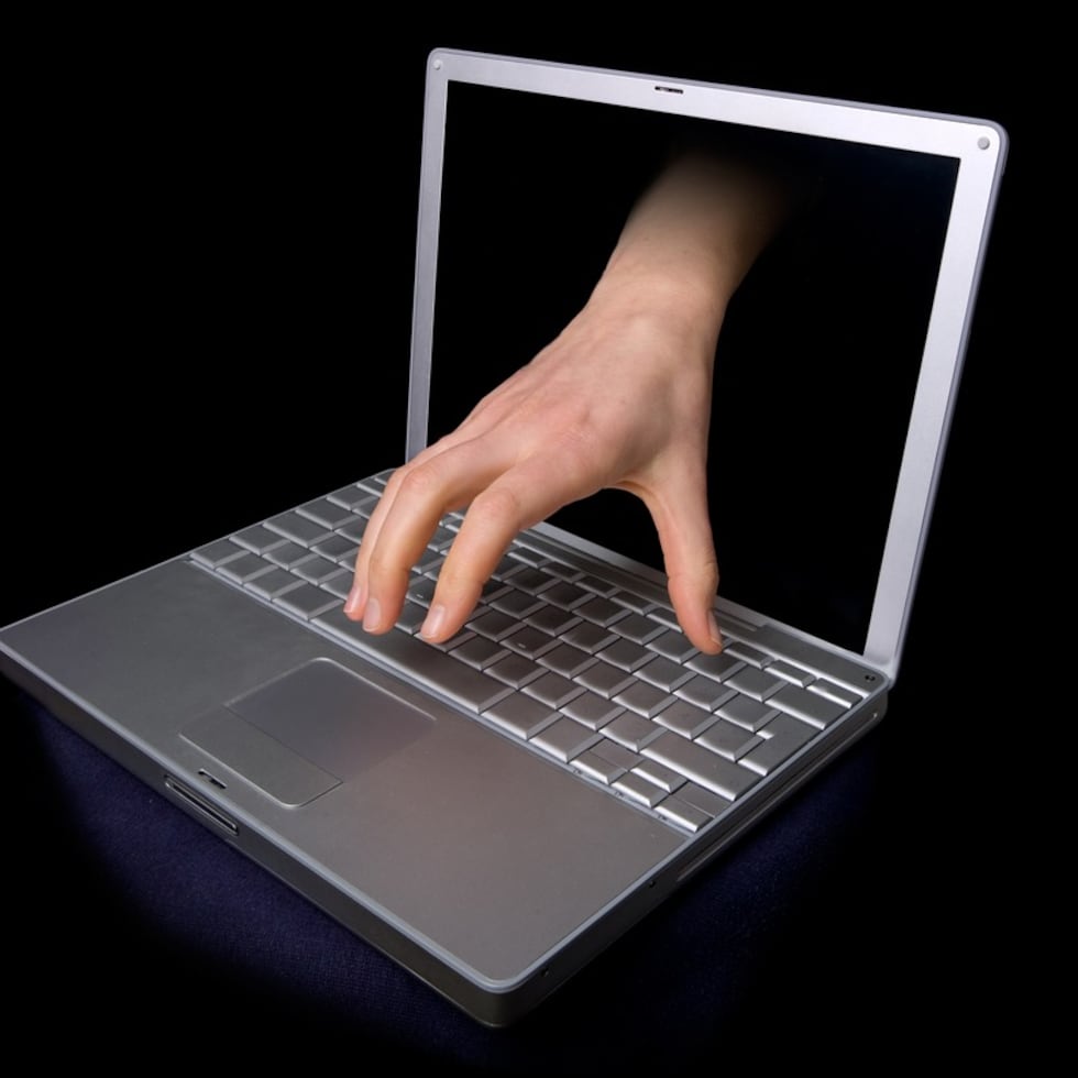 A hacker concept image of a hand coming through the computer. computer virus