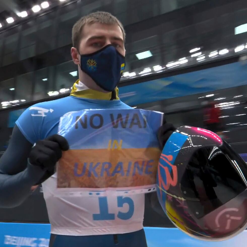 En imagen del video, el ucraniano Vladyslav Heraskevych sostiene un letrero con la leyenda "No a la guerra en Ucrania" tras terminar su competencia en el skeleton masculino en los Juegos Olímpicos de Pekín, este viernes.