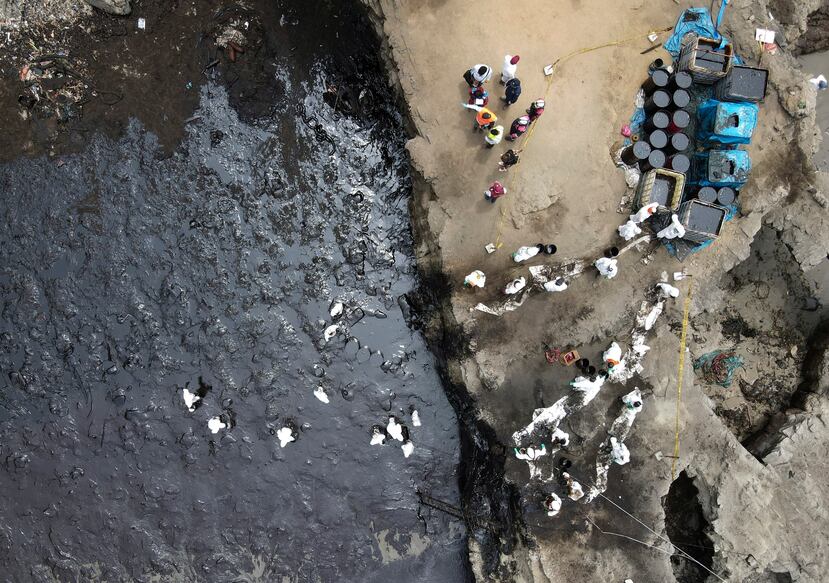 Los trabajadores continúan en una campaña de limpieza después de un derrame de petróleo, en Playa Cavero en el distrito de Ventanilla de Callao, Perú.