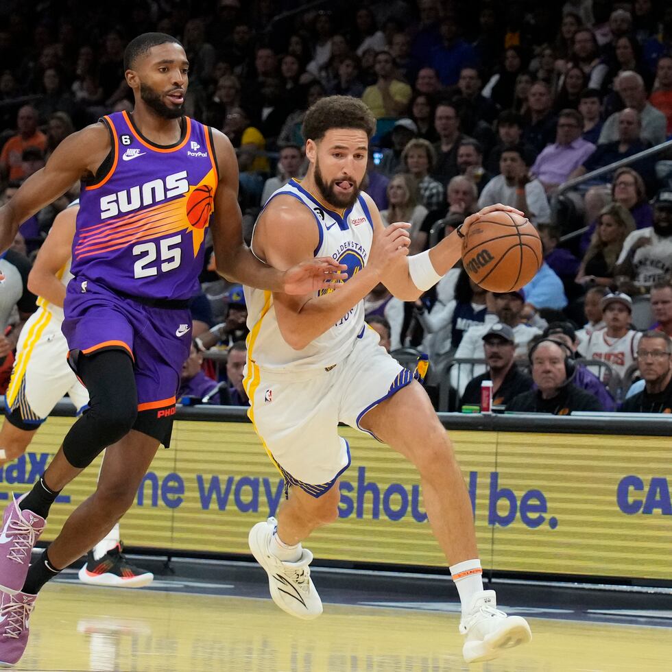 Klay Thompson, de los Warriors de Golden State, lleva el balón junto a su rival de los Suns de Phoenix Mikal Bridges (25) en la primera mitad del juego.