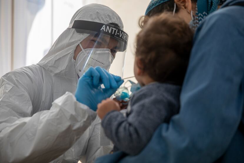 Una enfermera le toma una muestra nasal a un niño para una prueba de COVID-19.