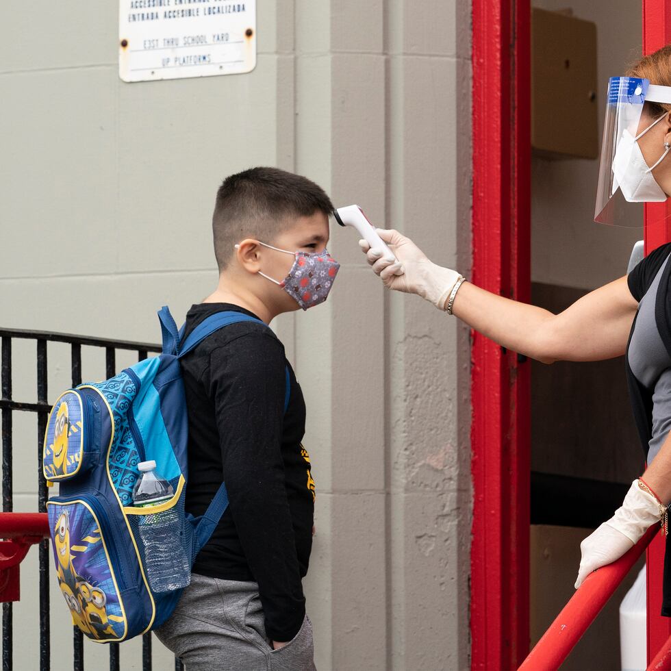 A student has his temperature taken before entering PS 179 elementary school in the Kensington neighborhood, Tuesday, Sept. 29, 2020, in the Brooklyn borough of New York. Hundreds of thousands of elementary school students are heading back to classrooms Tuesday as New York City enters a high-stakes phase of resuming in-person learning during the coronavirus pandemic. (AP Photo/Mark Lennihan)