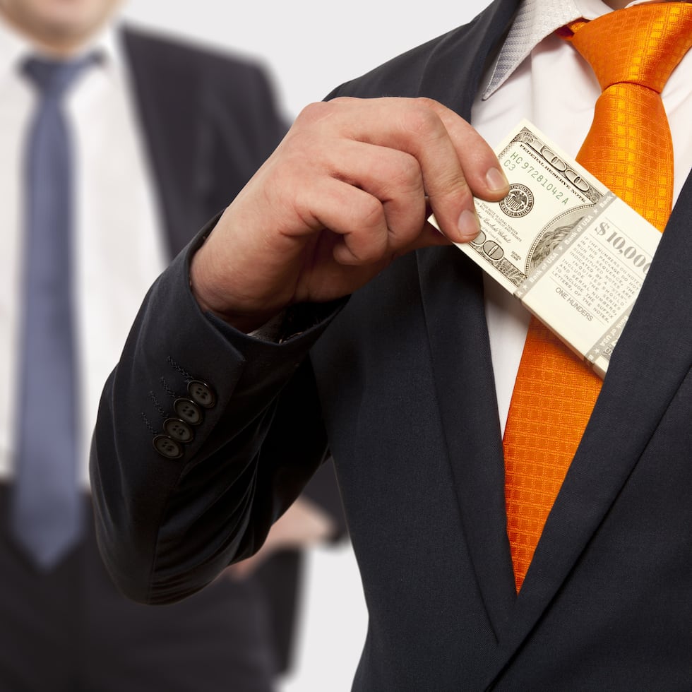 Businessman putting money in suit jacket pocket, concept for corruption, bribing