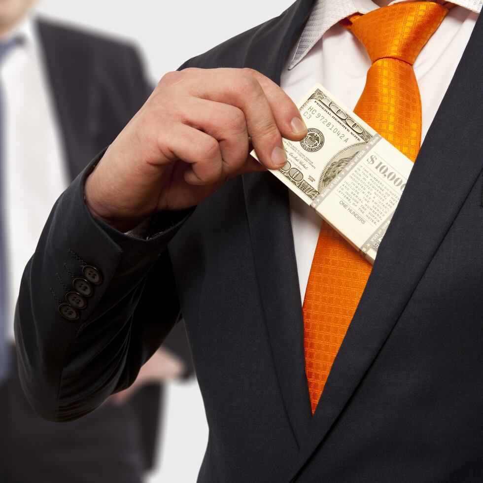 Businessman putting money in suit jacket pocket, concept for corruption, bribing