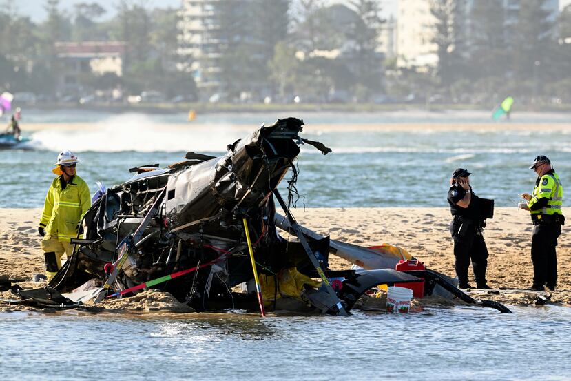 Trabajadores de emergencias revisan un helicóptero en el sitio de un accidente cerca de Seaworld, en Gold Coast, Australia, el lunes 2 de enero de 2023.