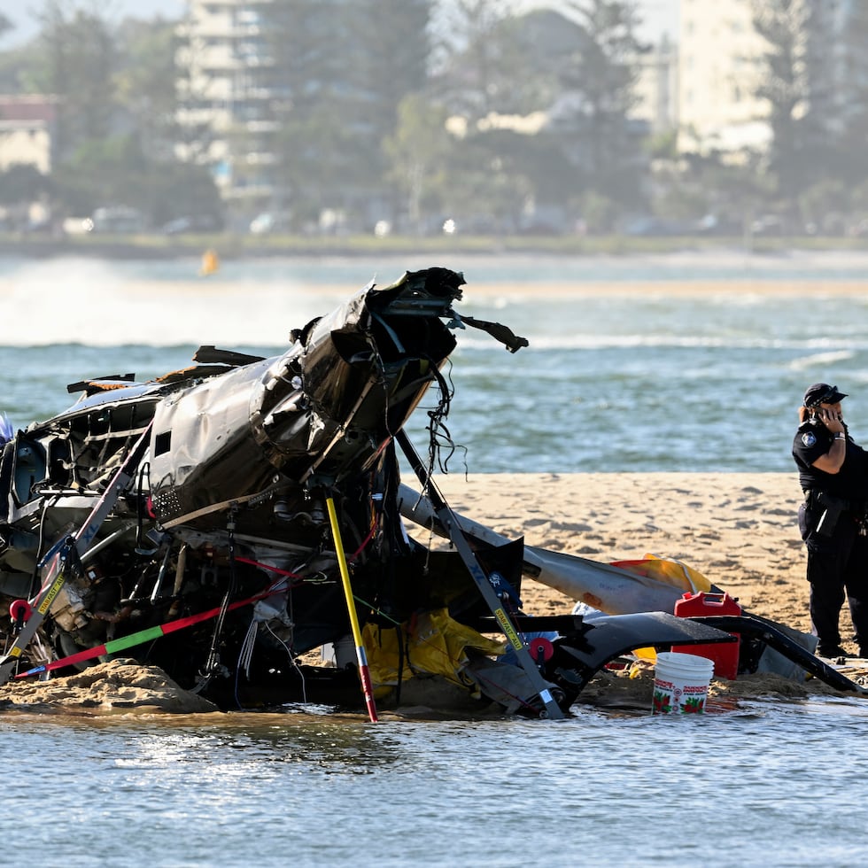 Trabajadores de emergencias revisan un helicóptero en el sitio de un accidente cerca de Seaworld, en Gold Coast, Australia, el lunes 2 de enero de 2023.