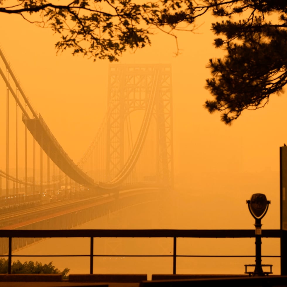 Un hombre conversa por su teléfono en medio de una bruma de humo cerca del puente George Washington, en esta imagen tomada desde Fort lee, Nueva Jersey, el miércoles 7 de junio de 2023. (AP Foto/Seth Wenig)