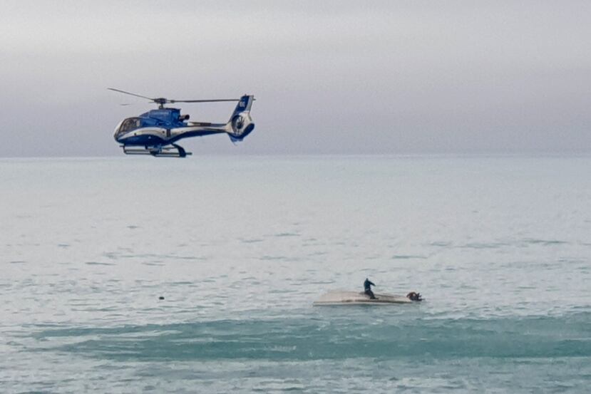 Un helicóptero sobrevuela un barco volcado con un sobreviviente sentado sobre el casco, en la costa de Kaikoura, Nueva Zelanda, el 10 de septiembre de 2022.