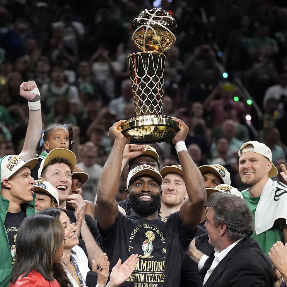 Jaylen Brown, centro, de los Celtics de Boston, alza el trofeo de campeonato Larry O'Brien mientras celebra con su equipo la conquista del título de la NBA.
