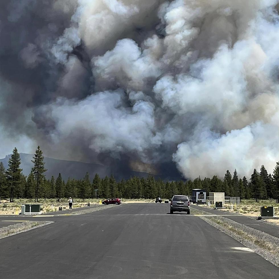 El humo de un incendio forestal se eleva desde una carretera cerca de La Pine. El fuego provocó evacuaciones obligatorias en la pequeña localidad del centro de Oregon y crecía con rapidez en un entorno seco y caluroso.