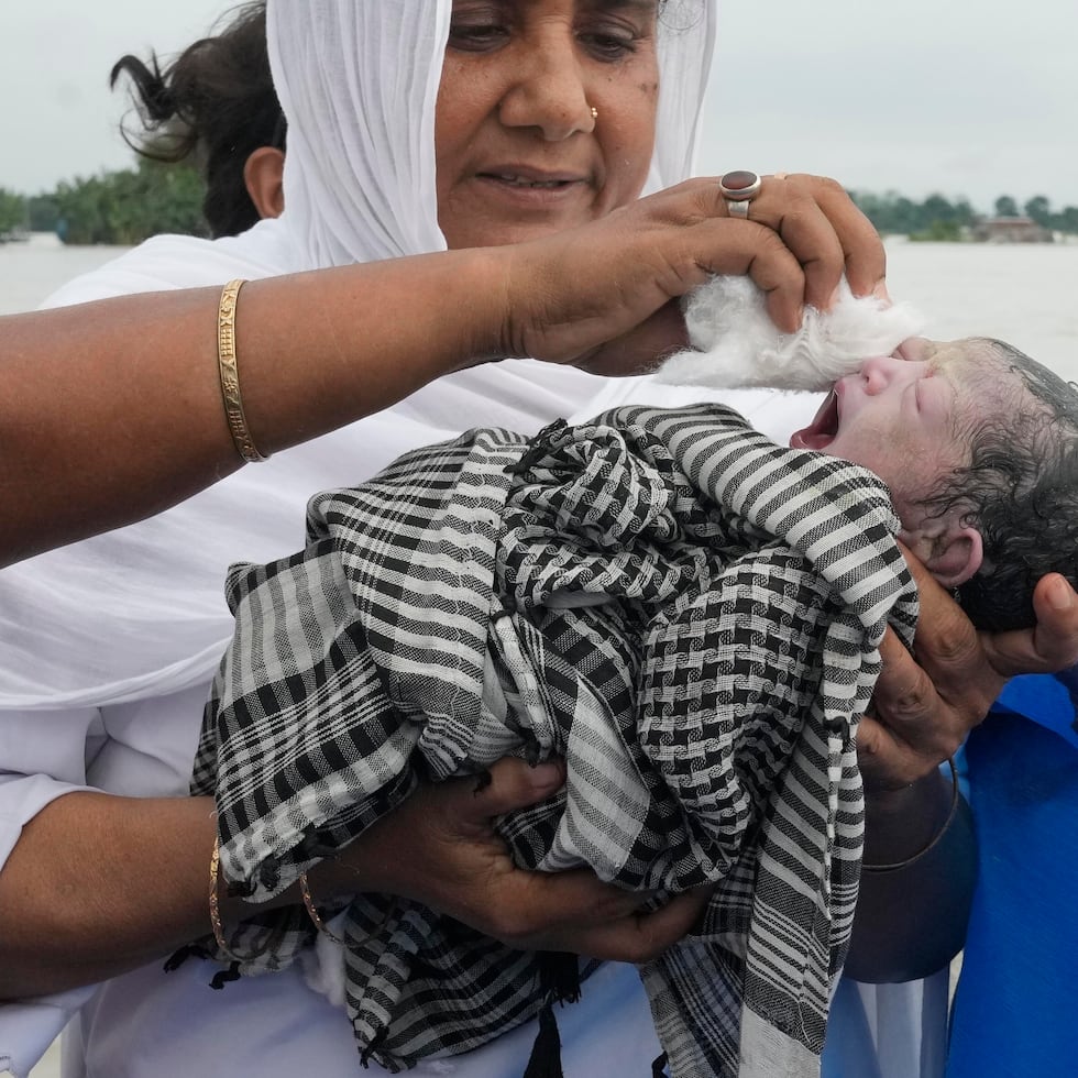 Diluwara Begum, una partera, sostiene a un bebé recién nacido después de ayudar en su parto en un barco sobre el río Brahmaputra, en el estado de Assam, en el noreste de India, el miércoles 3 de julio.