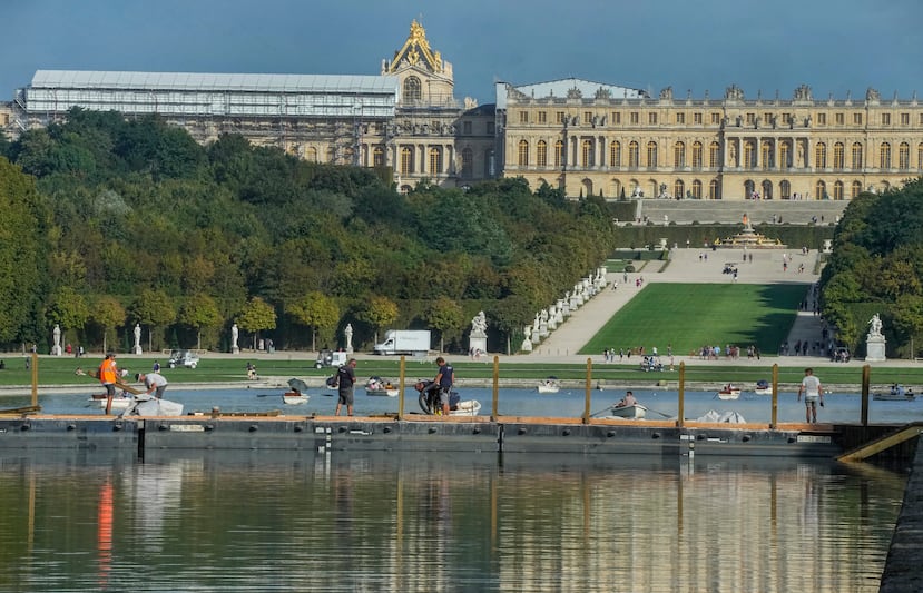 Trabajadores de la construcción están de pie sobre un puente de pontones que cruza el Gran Canal del jardín del Chateau de Versailles para el evento ecuestre de campo a través durante los Juegos Olímpicos de París 202.