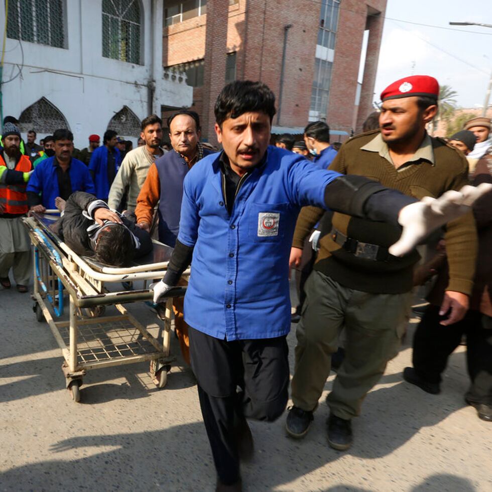 Trabajadores transportan a una de las víctimas lesionadas tras la explosión de una bomba en un ataque suicida en Peshawar, Pakistán.