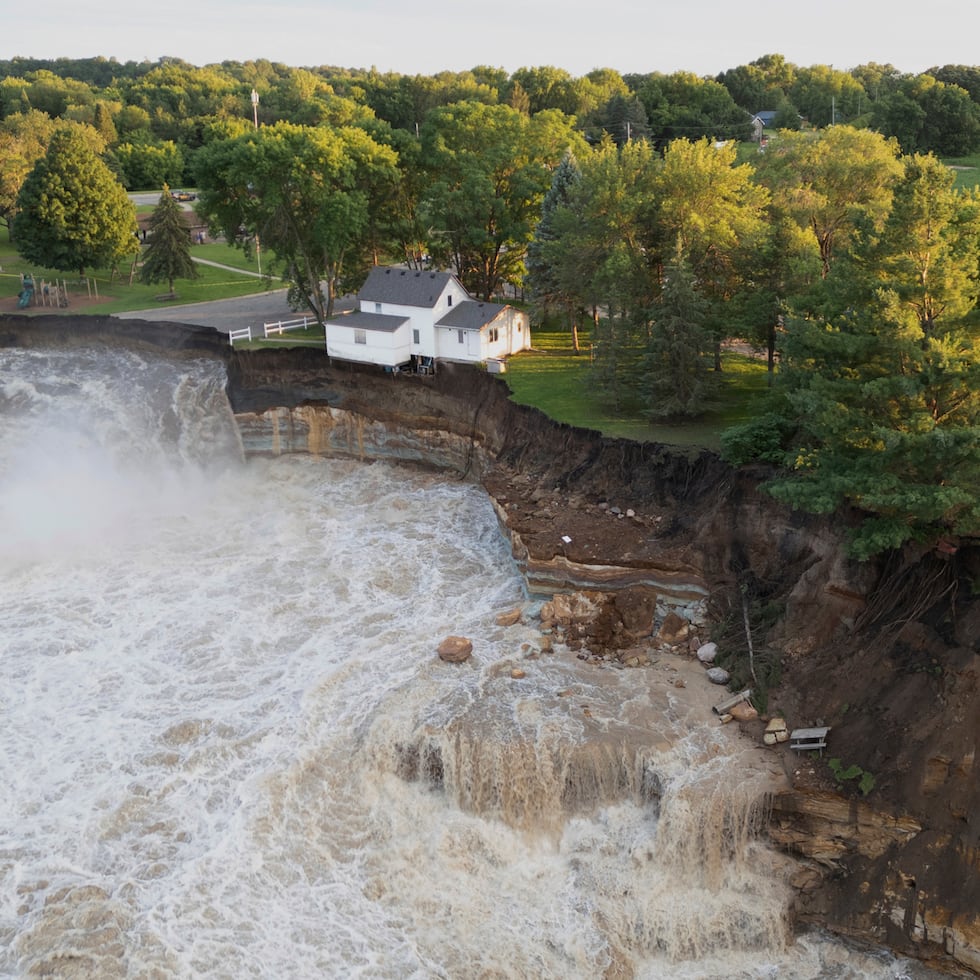 En esta foto, tomada con un dron y proporcionada por AW Aerial, se muestra una casa tambaleándose antes de derrumbarse parcialmente en el río.