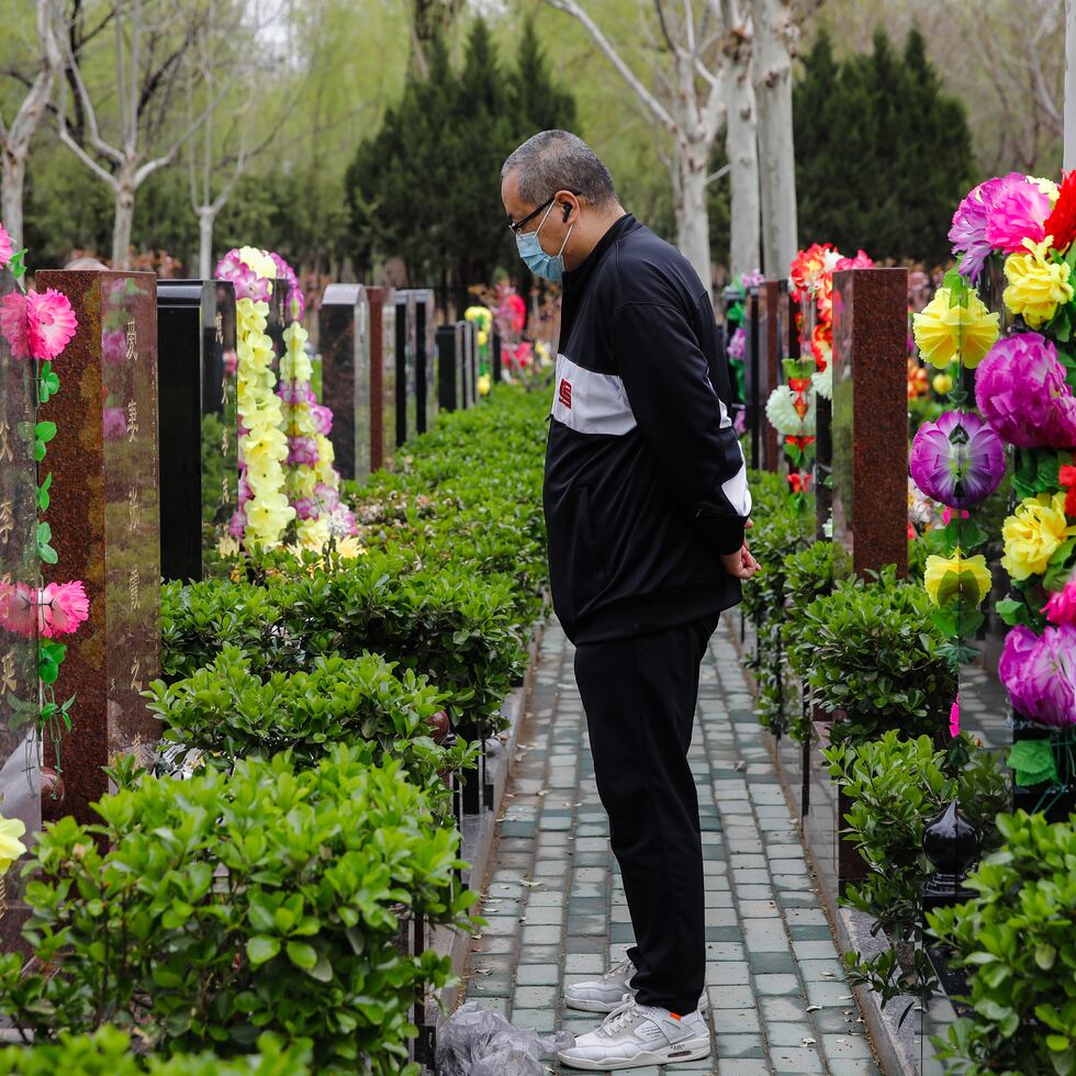 Foto de archivo de un hombre frente a una tumba en el Cementerio Waiqiao en Pekín.