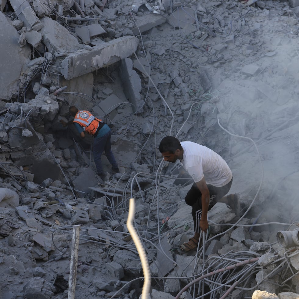 Palestinos buscan cadáveres y sobrevivientes entre los escombros de un edificio residencial destruido por un ataque aéreo israelí.