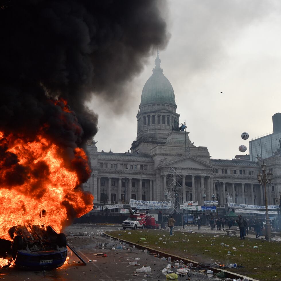Un automóvil arde durante enfrentamientos entre la policía y manifestantes antigubernamentales frente al Congreso, donde los senadores debaten proyectos de ley promovidos por el presidente argentino Javier Milei en Argentina.
