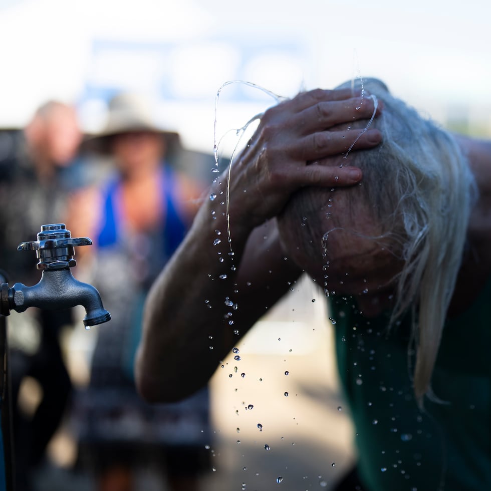 Una persona se refresca durante el festival de blues de Waterfront, el viernes 5 de julio, en Portland, Oregon. Los aficionados a la música enfrentaron el calor bebiendo agua fría, buscando refugio en la sombra o refrescándose bajo ventiladores de rocío.