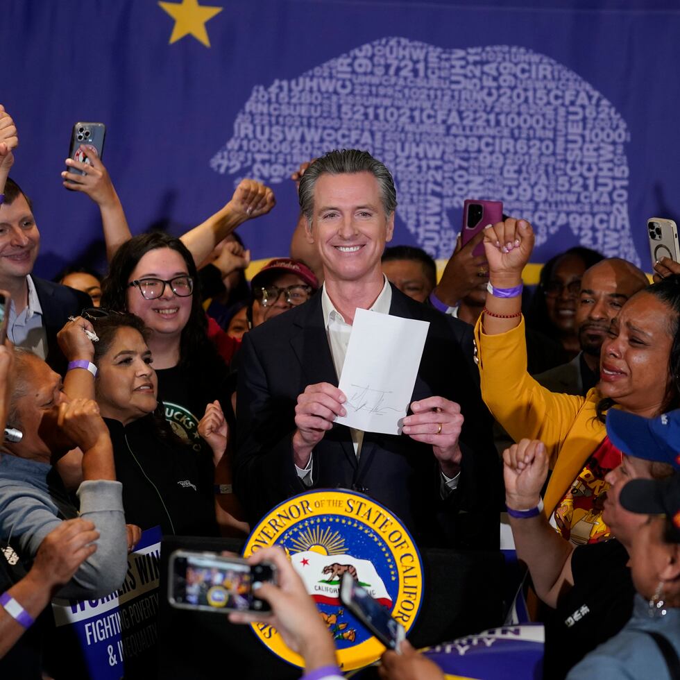 El gobernador de California, Gavin Newsom, muestra que ha firmado un proyecto de ley sobre comida rápida rodeado de trabajadores de ese sector en el Local 721 del sindicato SEIU en Los Ángeles, el jueves 28 de septiembre de 2023.